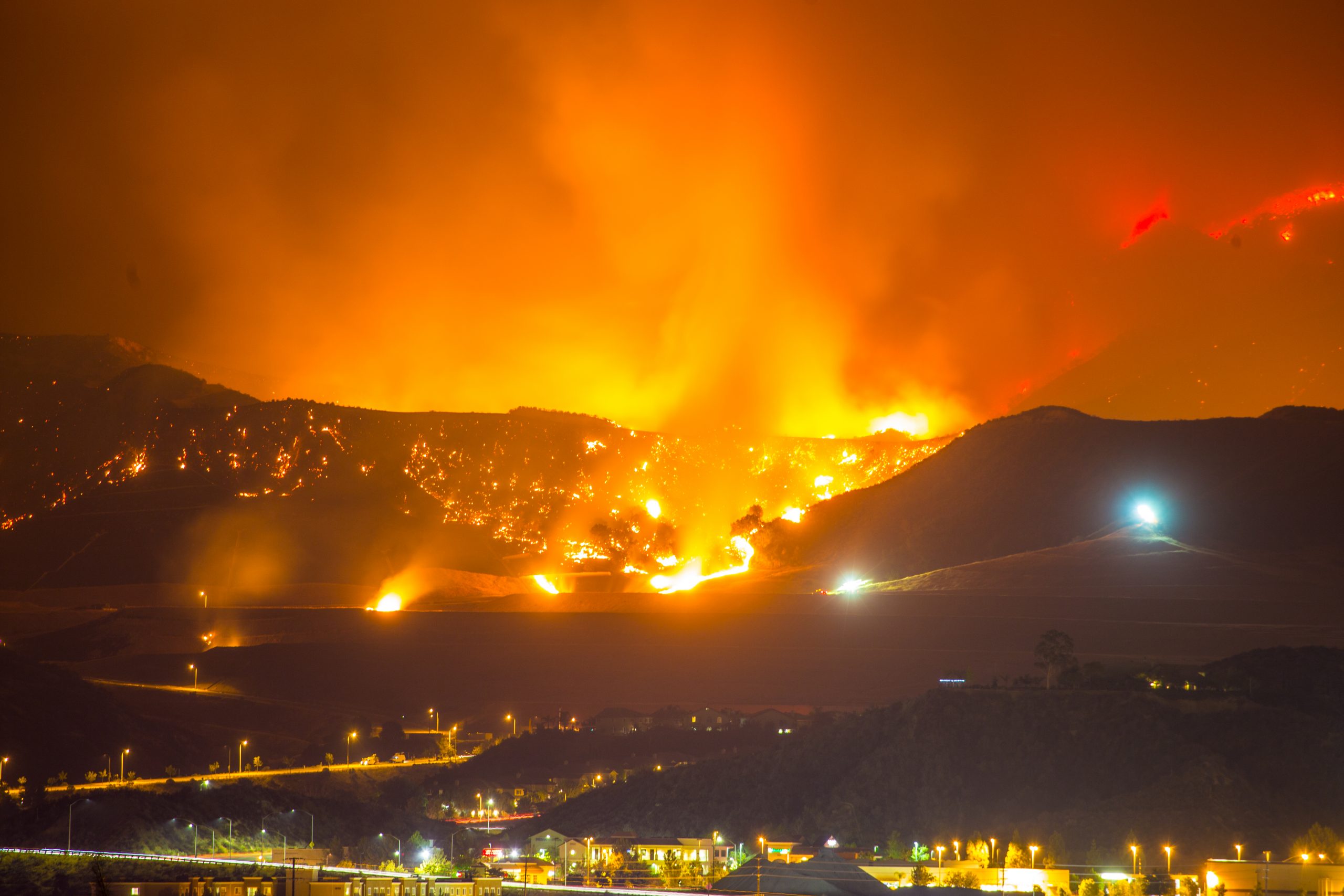 Nighttime photo of a Southern California wildfire in mountains and threatening homes and businesses