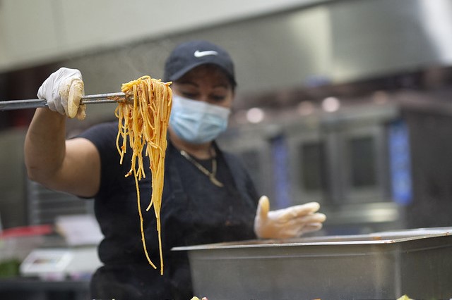 A restaurant worker prepares a tong-full of delicious spaghetti.